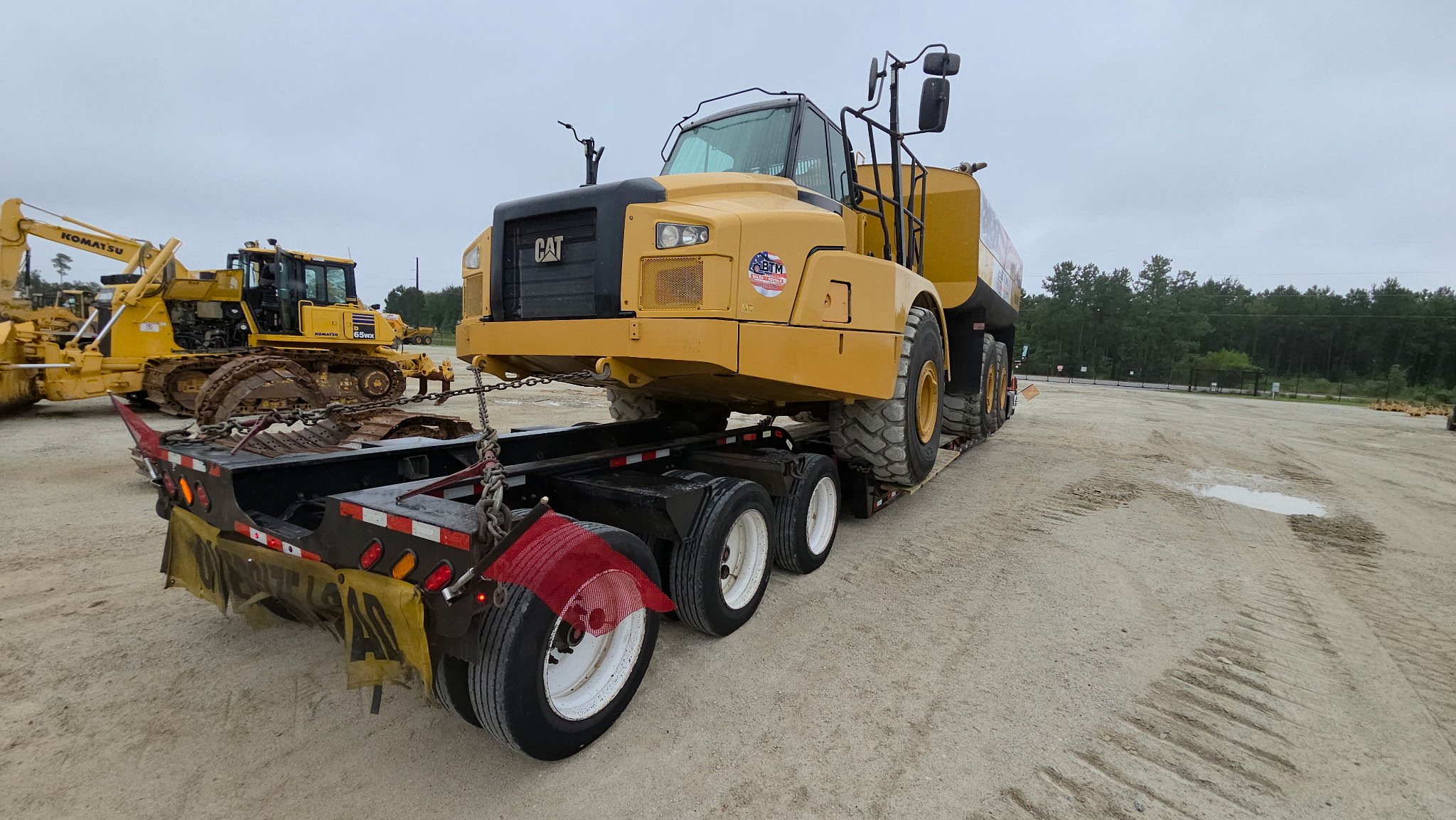 CAT water truck chained on a multi-axle lowboy trailer